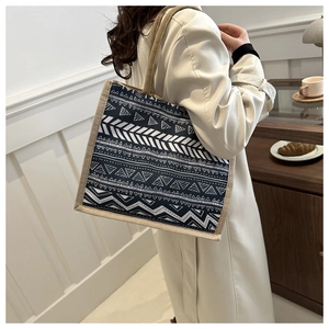 Bohemian linen tote bag with navy geometric patterns shown over the shoulder in a cafe setting