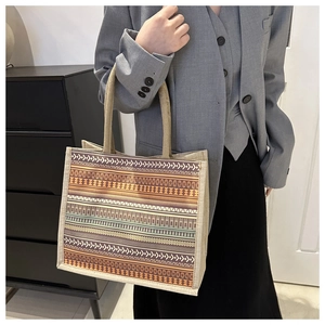 Detail of bohemian tote bag with geometric patterns held by model in professional suit
