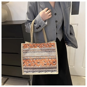 Close-up of Bohemian linen tote bag with orange ethnic floral pattern and woven handles