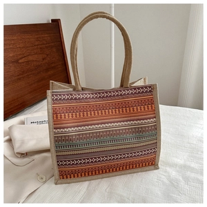 Detail of bohemian burlap tote bag featuring ethnic geometric patterns and woven handles