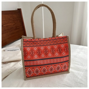Detail of bohemian jute tote bag with orange geometric patterns and braided rope handles