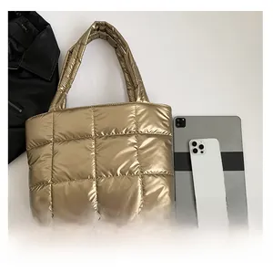Macro shot of metallic golden quilted tote bag with tablet and phone for size comparison