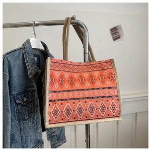 Detail of bohemian orange tote bag with ethnic pattern hanging on a metal rack
