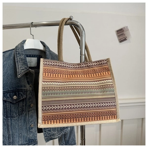 Detail of woven jute tote bag with ethnic tribal patterns on a clothing rack