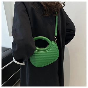 Detail of green crossbody bag with vertical stripe texture and circular cutout handle