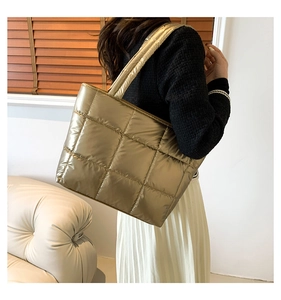 Macro detail of quilted gold tote bag featuring glossy metallic finish and square patterns