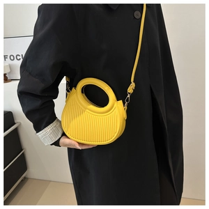 Detail of bright yellow semi-circle leather handbag with vertical texture and metal strap