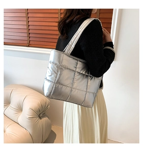 Detail of silver metallic quilted tote bag worn by model in a casual lifestyle setting