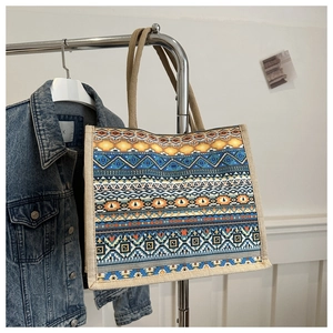 Detail view of large linen tote bag with colorful ethnic geometric patterns on a hanger