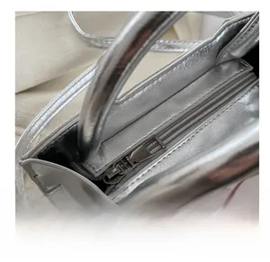 Close-up of smooth metal zipper and silver mirror finish texture on fashion handbag