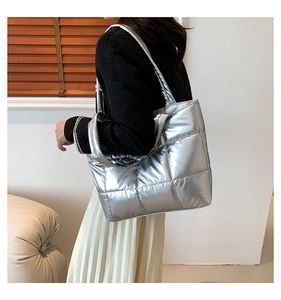 Side view of silver quilted tote bag worn by model in a minimalist room with natural light