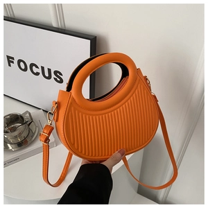 Detail der orangefarbenen halbrunden Handtasche mit vertikaler Streifenstruktur und Rundgriff