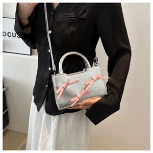 Detail showing the silver metallic square bag with pink satin bows and shoulder strap