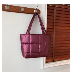 Détail d'un sac cabas matelassé violet métallisé suspendu à un crochet en bois