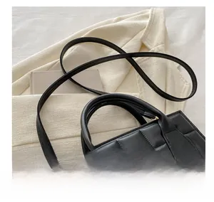Detail of black quilted leather handbag with gold hardware and adjustable strap on a book