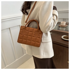 Close-up of caramel brown quilted leather handbag with gold hardware and top handles
