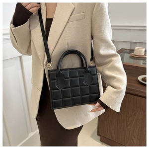 Detail of black quilted leather handbag showing 3D square texture and golden metal hardware