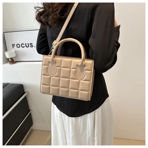 Chic beige quilted square handbag worn crossbody, detailed side view on model