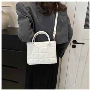 Detail of white quilted PU leather handbag with gold hardware shown on a female model