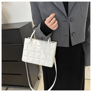 Chic white quilted handbag with adjustable strap shown on model in a minimalist room