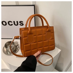 Detail of brown quilted texture on structured square handbag with faux leather finish