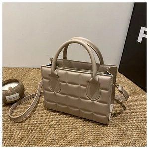 Macro detail of beige quilted square texture on a stylish faux leather tote handbag