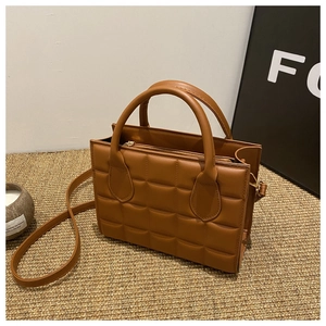 Detailed macro view of the caramel brown quilted faux leather texture on the tote bag