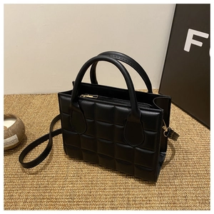 Detail of the black quilted crossbody bag showing square pattern and round handles