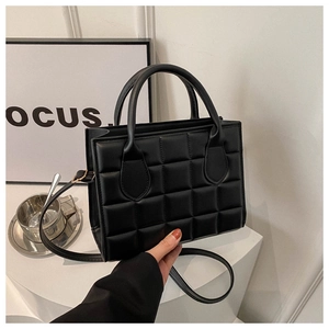 Detail of black quilted square pattern texture on a minimalist crossbody handbag