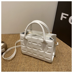 Close-up of quilted pattern and top handle on white faux leather crossbody bag