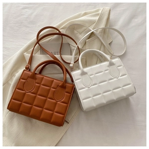 Detail of quilted leather handbags in caramel and white with textured square pattern