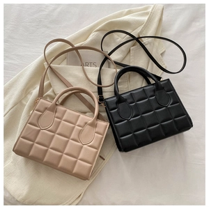 Detail shot of beige and black quilted handbags featuring a premium textured leather finish