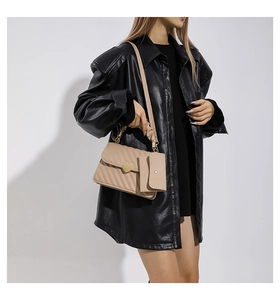 Detail of beige quilted shoulder bag with heart-shaped metal lock on a model