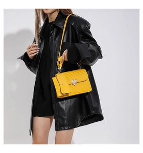 Detail of yellow quilted crossbody bag with golden heart clasp and mini pouch