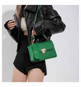 Detail of bright green pleated crossbody bag with golden heart buckle and small coin pouch