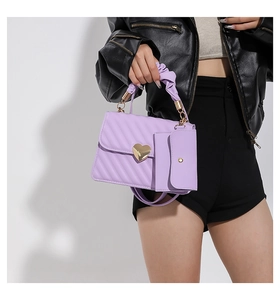 Detail of lavender quilted small square bag featuring golden heart buckle and cloud handle