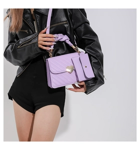 Close-up of purple crossbody bag with golden heart clasp and mini pouch accessory