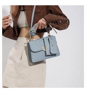 Detail of light blue pleated handle shoulder bag with golden heart buckle and mini pouch