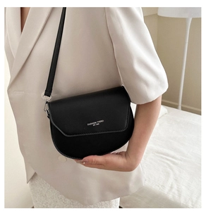 Gros plan sur le sac besace demi-lune noir avec lettrage porté par un mannequin à la main