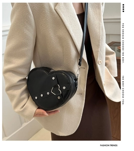 Détail du sac noir en forme de cœur avec rivets argentés et fermoir métallique