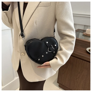 Détail du sac bandoulière en forme de cœur avec clous argentés et boucle métallique