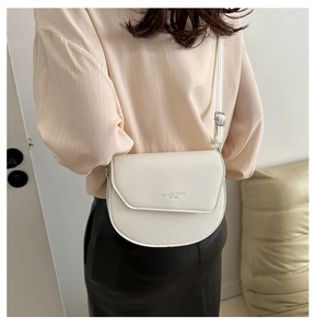 Détail du sac à main bandoulière blanc crème avec sangle réglable et logo embossé