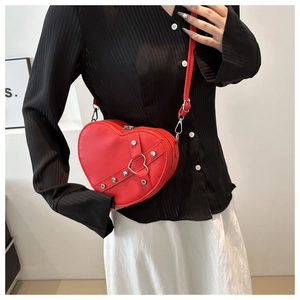 Détail du sac bandoulière rouge en forme de cœur avec lanières à rivets et boucle métal