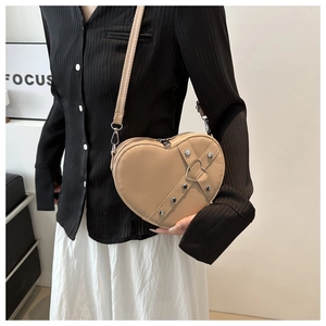 Détail du sac bandoulière en forme de cœur avec lanières rivetées et anneau argenté