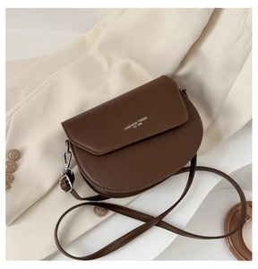 Détail d'un sac besace marron en cuir avec logo blanc et boucles métalliques argentées