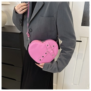 Vue détaillée du sac rose en forme de cœur avec clous argentés et boucle sur la bandoulière