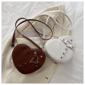 Détail de sacs bandoulière en forme de cœur avec rivets en métal et texture cuir PU mat