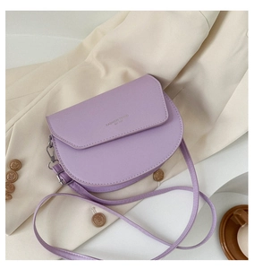 Détail d'un sac bandoulière demi-lune violet clair sur fond de blazer beige chic