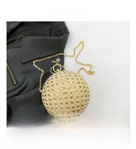 Detail of gold hollow spherical evening bag with laser-cut patterns and ring handle