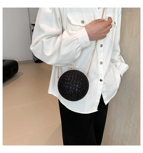 Detail shot of a black sequined spherical evening bag with gold chain and ring clasp